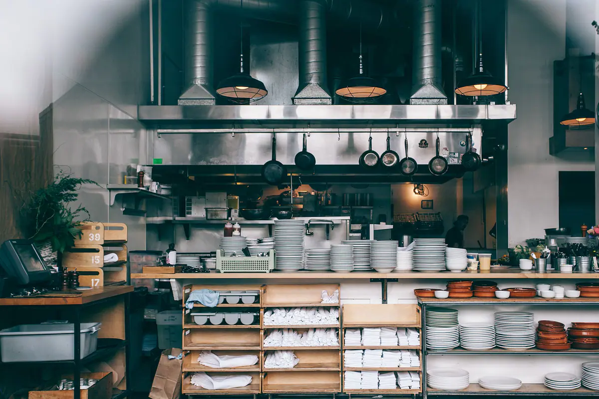 A restaurant kitchen with plates and cookware stacked on open shelving